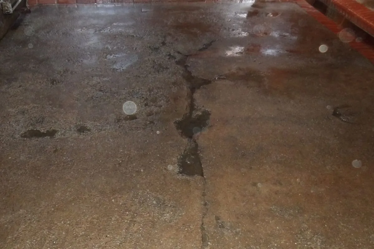Rissbildung im Betonboden eines Sonderbauwerks vor der Sanierung mit sichtbaren Feuchteschäden